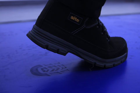 A shoe lifting from a blue LabTACK mat